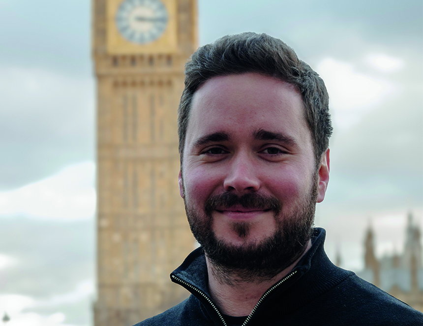 Ash Corbett-Collins wearing a zipped black fleece and black t-shirt with Big Ben clock tower out of focus behind him