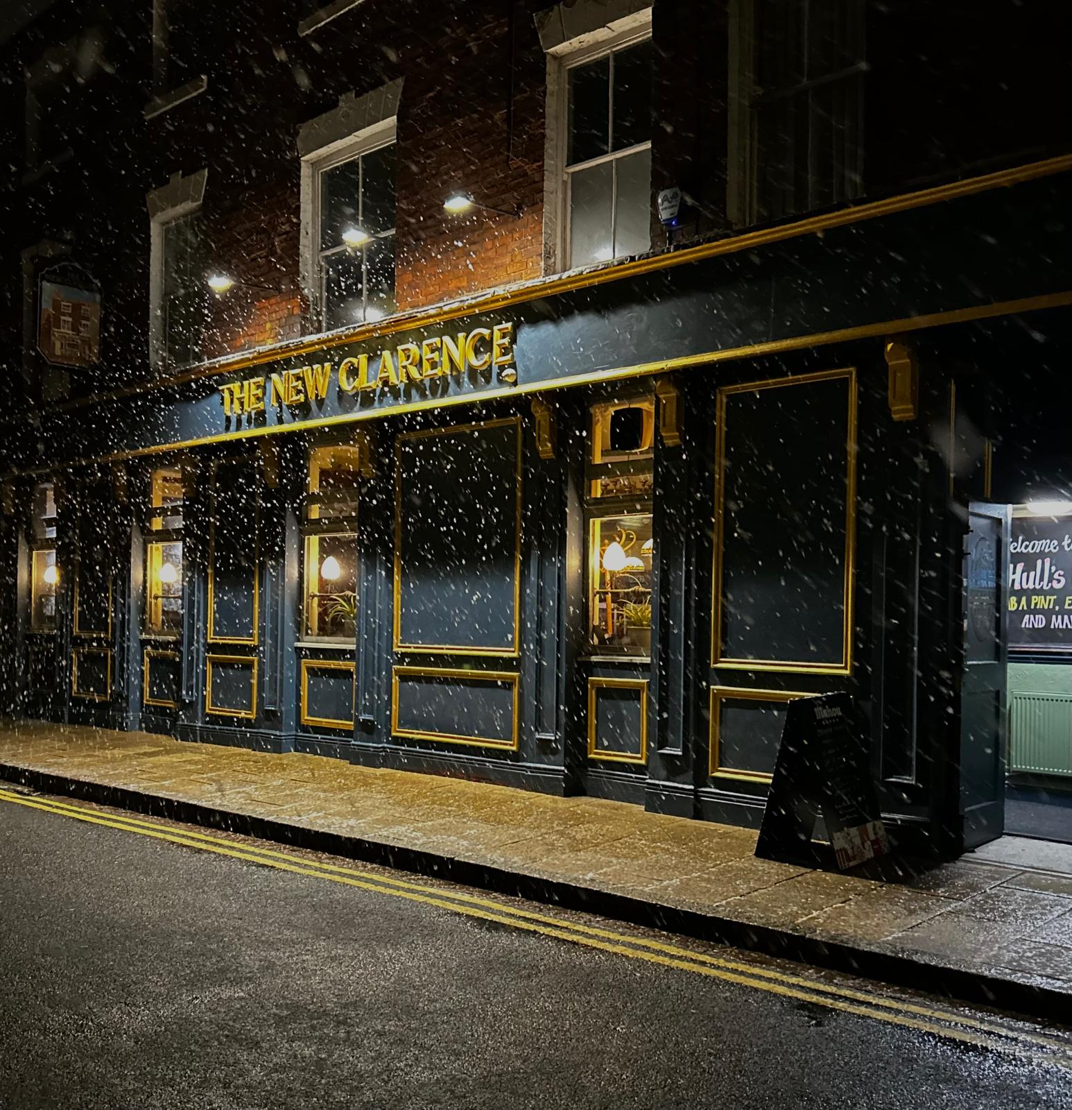 Photo of the exterior of the New Clarence, Hull in the rain. The exterior is a black and gold, with the name of the pub done in gold writing.