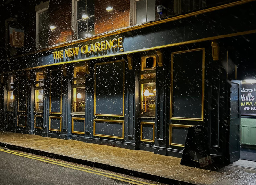 The exterior of the New Clarence lit up at night on a snowy evening