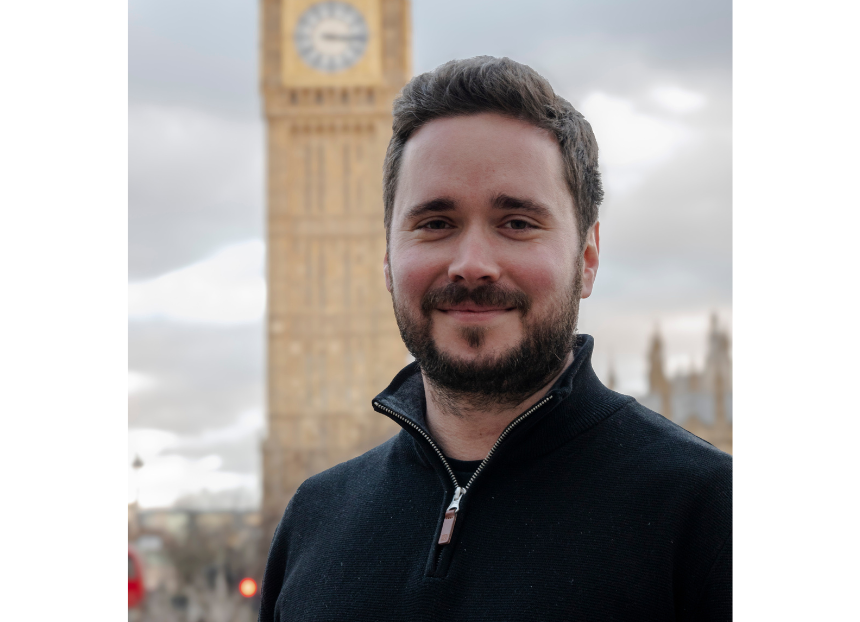 Ash Corbett-Collins wearing a zipped black fleece and black t-shirt with Big Ben clock tower out of focus behind him